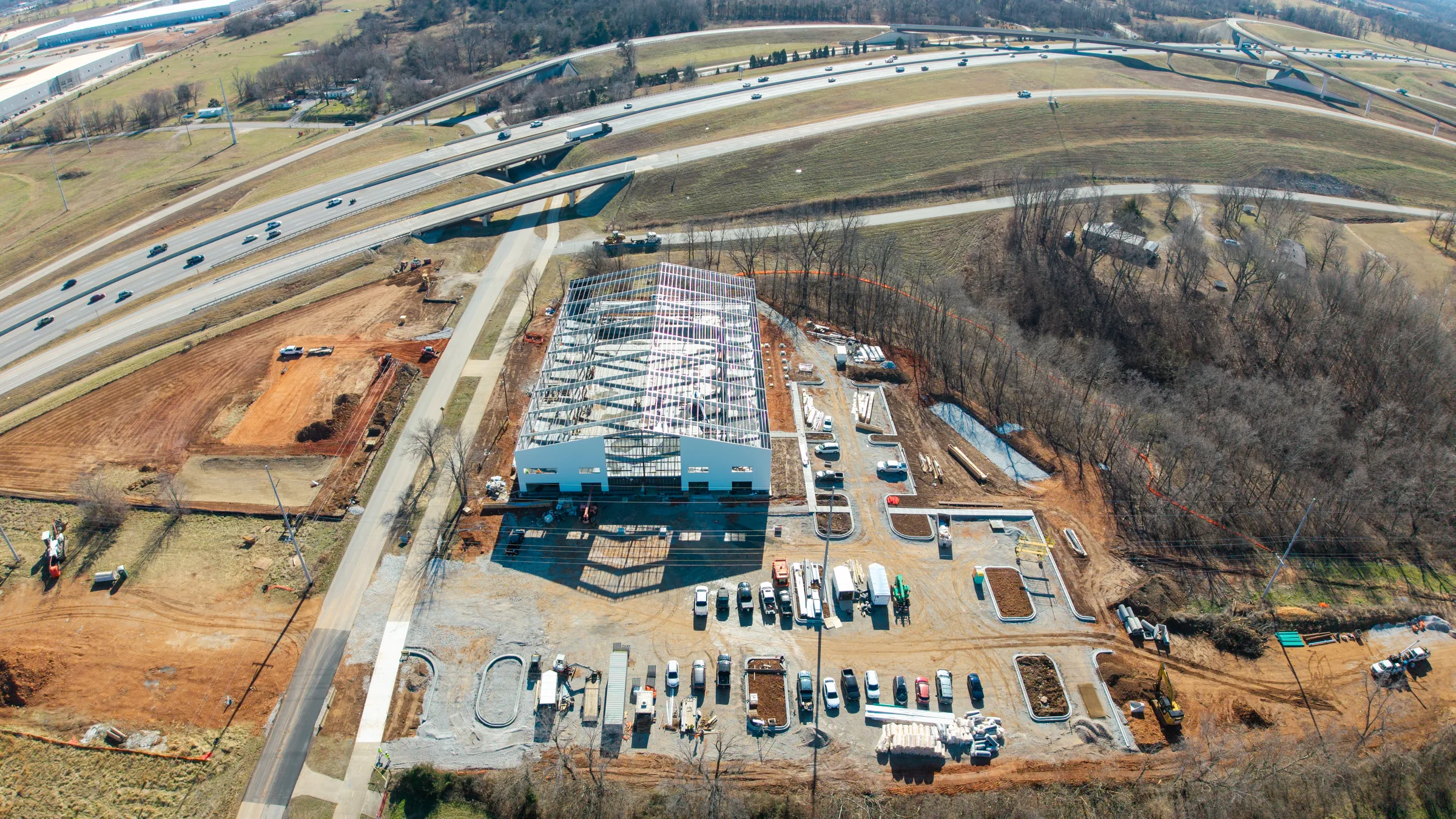 Aerial view of large-scale commercial construction site near highway interchange, Northwest Arkansas